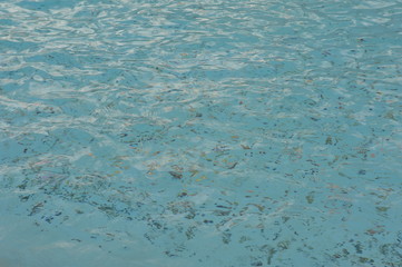 money coins in the clear water of the fountain in summer