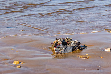 Clothes and rubbish washed up onto sand beach by the Atlantic Ocean, Agadir, Morocco