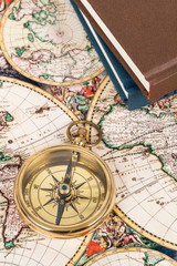 Compass on vintage ancient map with book, concept for direction transportation and travel