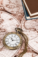 Vintage pocket watch clock on ancient map background with books