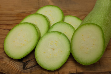 Sliced green zucchini on wooden background, copy space. Healthy food, green vegan diet, raw recipes.