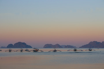 Fototapeta premium Calm morning on Philippines island with traditional boats. Sunrise on Palawan, Philippines. Tropical isles in morning dusk. Asian landscape. Summer vacation. Travel and transport concept.