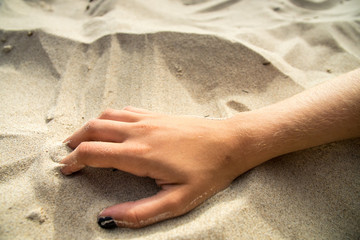 Hand in beach sand