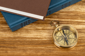 Compass on wooden background with vintage book, concept for direction transportation and travel, with copy space