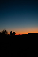 Fototapeta premium People sitting in dark sunset looking to horizon