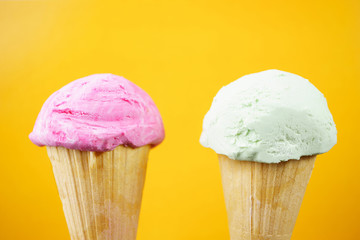 Strawberry and pistachio ice-cream scoops in waffle ice cream cones on pastel background. Summer, heat, vacation,choice, refreshment, traditional seasonal cold sweets