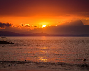 Surfer riding wave during sunset with scenic background landscape