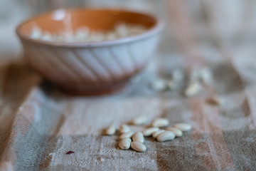 White beans in a clay deep plate and on a linen tablecloth, soft focus