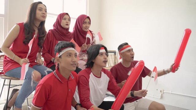 excited young indonesian supporter watching a match together in cafe