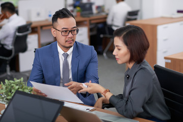 Asian business partners working together at the table they reading business contract and discussing it in team