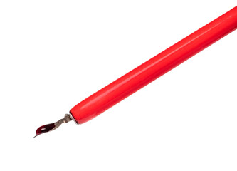 big red ink drop atop of sharp nib of dip pen