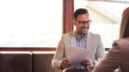 Young bearded handsome businessman with glasses is very pleased because in his hands he keeps very...