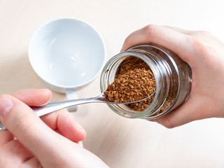 hand spooning up instant coffee from jar close up