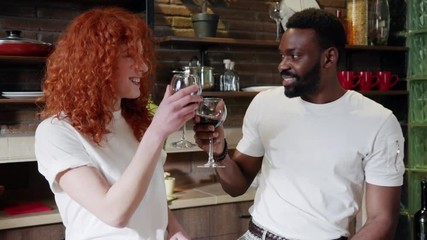 Multiracial couple of mature friends raising a toast with glasses of red wine indoor at home in the kitchen. Close up hands of men and women toasting with wine. Close up shot of lovers� hands cheering - Powered by Adobe