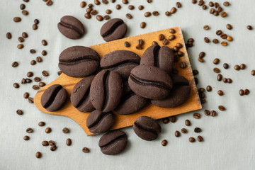 ginger biscuits with cocoa in the form of coffee beans on a wooden board on a gray background