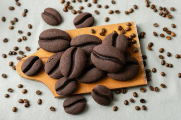 ginger biscuits with cocoa in the form of coffee beans on a wooden board on a gray background