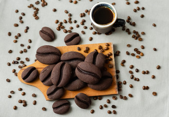 ginger biscuits with cocoa in the form of coffee beans on a wooden board on a gray background