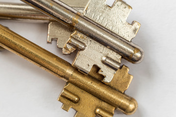 Close-up detail of old metallic keys stainless and yellow isolated on white background. Safety and security concept.