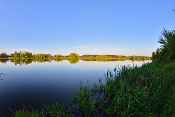 Błękitne niebo o zachodzie słońca nad spokojną wodą.