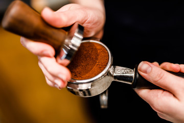 female barista prepare the ground coffee portion for professional espresso machine