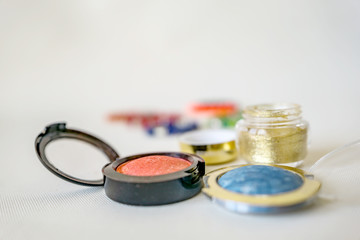 Close up of set of makeup, blush, shadows, on the white background. Modern colors with shine and fine glitter. Shallow depth of focus. Concept fashion and beauty.