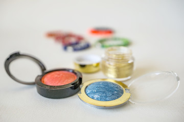 Close up of set of makeup, blush, shadows, on the white background. Modern colors with shine and fine glitter. Shallow depth of focus. Concept fashion and beauty.