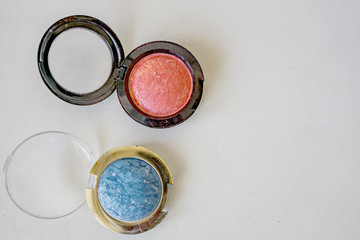 Close up of set of makeup, blush, shadows, on the white background. Modern colors with shine and fine glitter. Shallow depth of focus. Concept fashion and beauty.