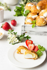 Profiteroles (choux à la crème) - French choux pastry balls filled with cottage cheese and cream with fresh strawberry, mint and cup of coffee.