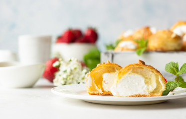 Profiteroles (choux à la crème) - French choux pastry balls filled with cottage cheese and cream with fresh strawberry, mint and cup of coffee.