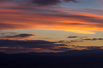 Amazing vivid colors of a sunset sky and clouds and distant horizon mountains