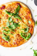 Pizza Margherita with fresh arugula (rucola) and mozzarella on a baking stone. Italian pizza.