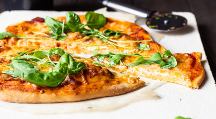 Pizza Margherita with fresh arugula (rucola) and mozzarella on a baking stone. Italian pizza.