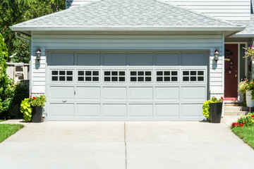 Wide garage door of residential house and concrete driveway in front - obrazy, fototapety, plakaty