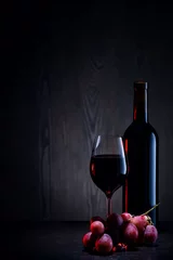 Fotobehang Red wine in glass and bottle and bunch of grapes on wooden table © alexlukin