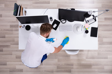 Janitor cleaning white desk in office