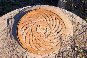Old manhole cover with the image of waves