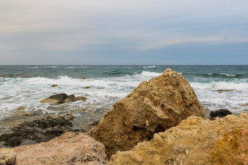 Fototapeta na wymiar waves splashes and wind on the sea stone beach with dramatic sky