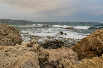 Fototapeta na wymiar waves splashes and wind on the sea stone beach with dramatic sky