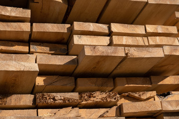 Wooden boards, lumber, industrial wood, timber. Pine wood timber stack of natural rough wooden boards on building site. Industrial timber building materials. Wood texture