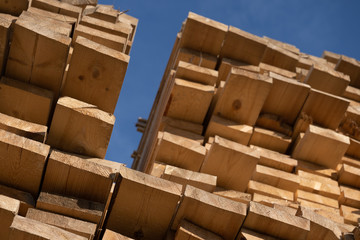 Wooden boards, lumber, industrial wood, timber. Pine wood timber stack of natural rough wooden boards on building site. Industrial timber building materials