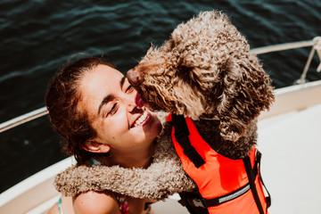 .Young and attractive woman enjoying a relaxing vacation on her boat playing with her lovely brown...
