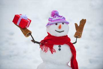 Snowman in a scarf and hat. Cute snowmen standing in winter Christmas landscape. Funny snowman in...
