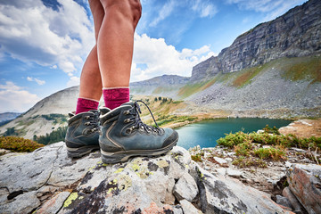 a young woman wearing hiking boots and trekking around an alpine mountain lake