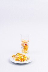 Different medicines and vitamins on a white background in a glass and a plate. Free space for text.