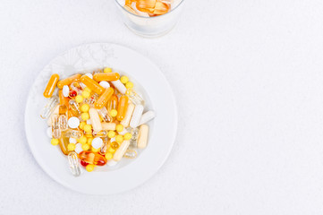 Different medicines and vitamins on a white background in a plate. Free space for text. View from above.
