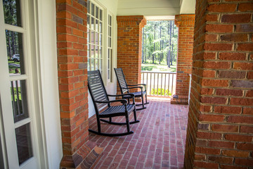 Fototapeta na wymiar Red Brick home front porch with black rocking chairs