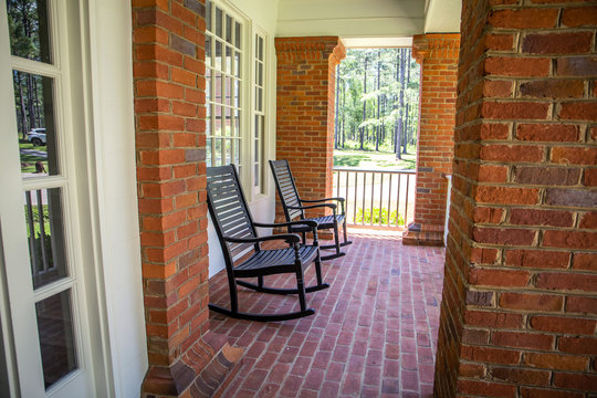 Red Brick Home Front Porch With Black Rocking Chairs