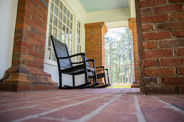 Red Brick home front porch with black rocking chairs