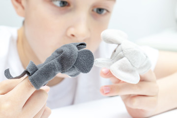 A caucasian boy playing different roles by using finger puppets, toys for expressing his emotions, agression, fear and freandship as a part of psychotherapy