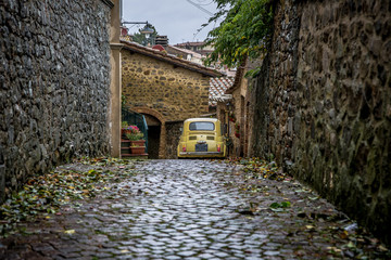 Street of the ancient town of Montalcino in Tuscany. Fiat 500 parked in an alley. Tuscany, Italy